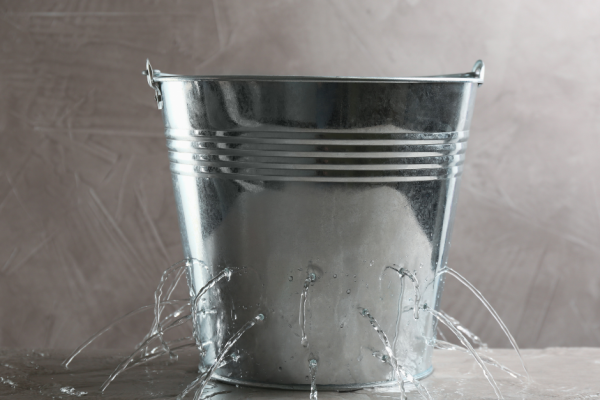 A bucket leaking water representing organisational (behavioural) leaks
